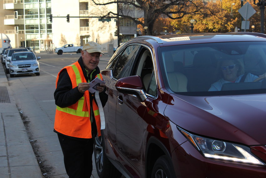 Mike Michalek takes a ballot from a voter at the drive-through drop  off site in front of the City and County Building on Election Day. He has worked at this site for the last four elections in Denver.
